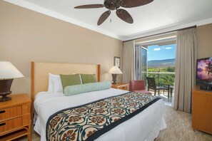 Habitación de hotel con cama, ventilador de techo, televisor, mesita de noche, silla y vistas al exterior.