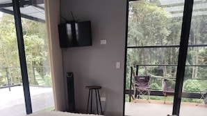 Een slaapkamer met een groot bed, een flatscreen televisie aan de wand en uitzicht op het landschap door grote ramen.