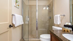 Een moderne badkamer met een douchecabine van glas, een toilet en een wastafel met toiletartikelen.
