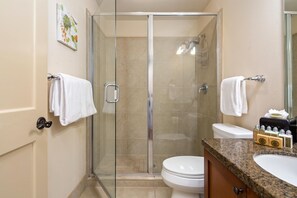 Une salle de bain moderne avec une douche à parois de verre, des toilettes et un lavabo équipé de produits de toilette.