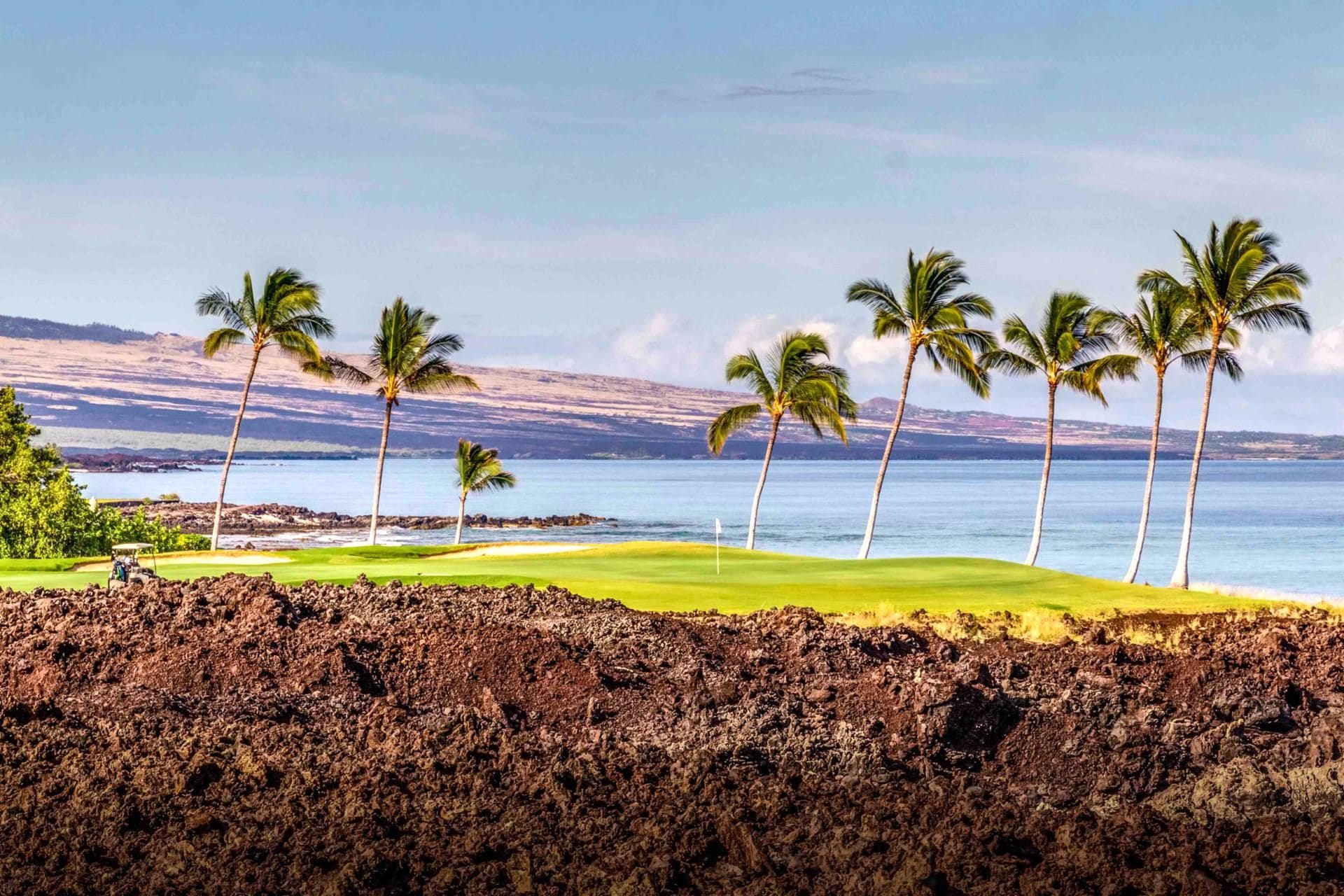 A golf course with a view of the ocean and mountains.