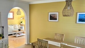 A dining area with a wooden table and chairs, a hanging light fixture, and framed pictures on the wall. - Peaceful Family Home in Brookvale for mid-term rental (Brookvale)