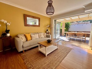 A living room with a sofa, coffee table, and a large window. - Peaceful Family Home in Brookvale for mid-term rental (Brookvale)