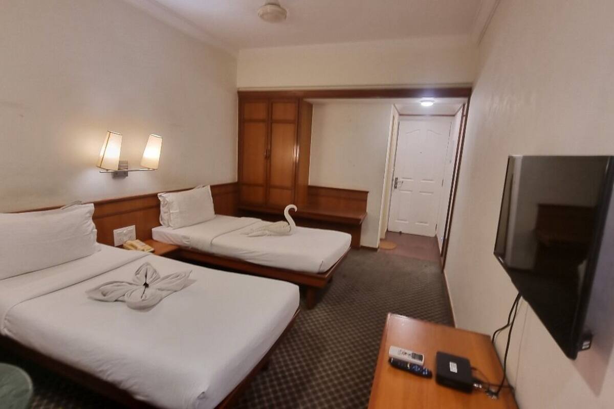 A hotel room with two beds, a TV, a desk, and a wardrobe.