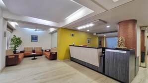 A reception area with a reception desk, a plant, and a sofa. - Hotel Skylon By Bizzgrow Hotels (Ahmedabad)