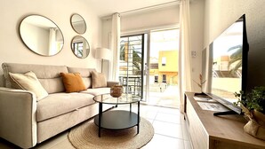 A living room with a sofa, a coffee table, a TV, and a balcony with a view. - Welooveyou Coral your place to discover the island (Costa Calma (incl. Urbanización Cañada del Río))