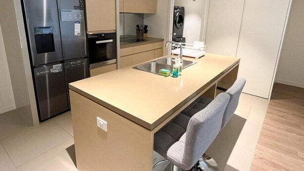 A compact kitchen with a built-in refrigerator, oven, and sink. - Luxury 2BR 2B Docklands Bright & Modern Apt - Free Covered Parking, 2p sofa bed (Docklands)