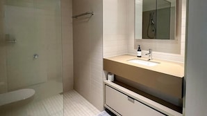 A modern bathroom with a glass shower enclosure, a sink with a mirror, and a toilet. - Luxury 2BR 2B Docklands Bright & Modern Apt - Free Covered Parking, 2p sofa bed (Docklands)