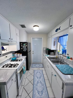 A compact kitchen with white cabinets, a gas stove, a refrigerator, and a microwave.
