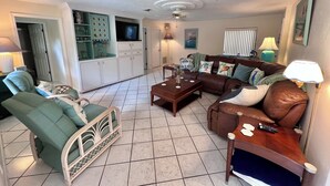 A living room with a sofa, armchair, coffee table, and a television.