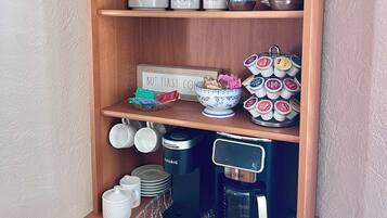 A wooden shelf with labeled containers for flour, coffee, and tea, a coffee maker, and a sign that says 'CAFE'.