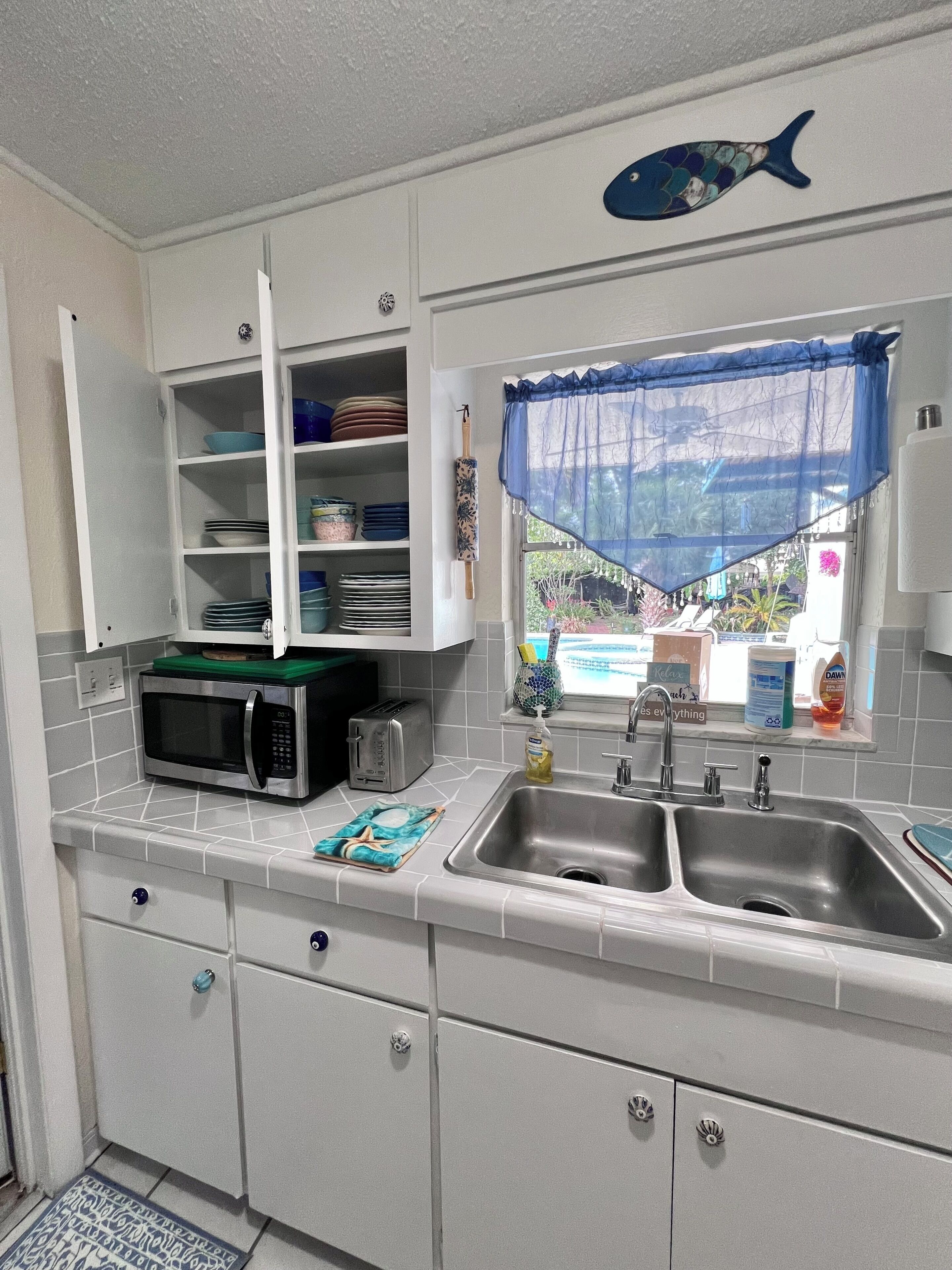 A kitchen with white cabinets, a microwave, a toaster, and a sink.
