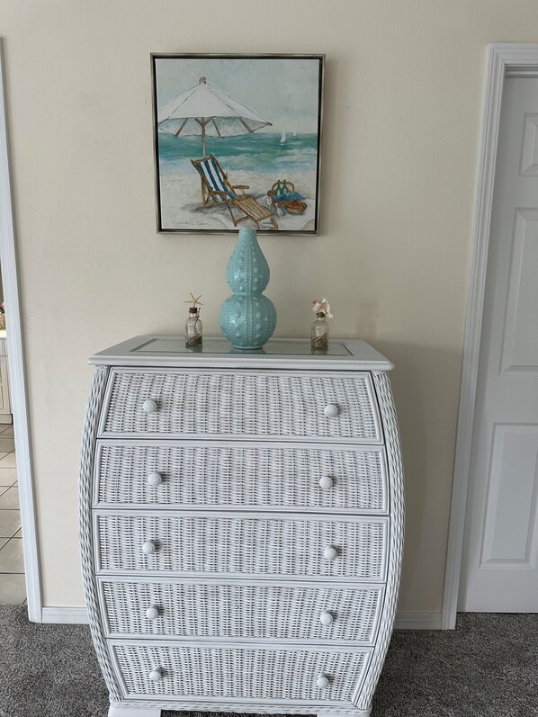 A white wicker console with drawers and a decorative vase on top.
