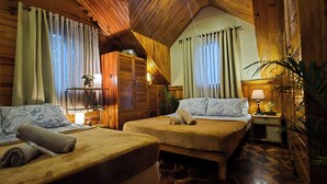 A cozy room with two beds, a wooden ceiling, and a small table with a lamp. - Blueridge Mountain Cabin (Baguio)