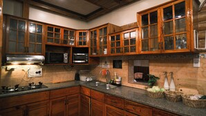A kitchen with wooden cabinets, a microwave, a toaster, and a sink. - Blueridge Mountain Cabin (Baguio)