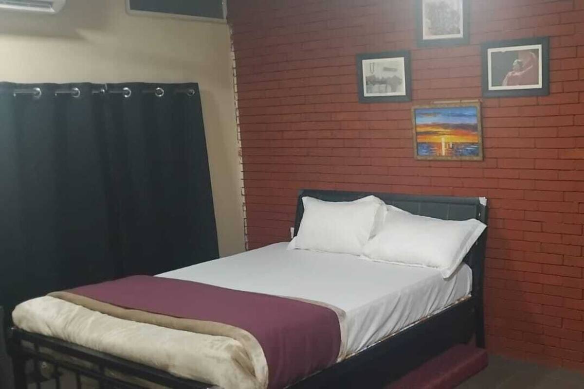 Ein Schlafzimmer mit einem Bett, einer Ziegelwand und drei gerahmten Bildern.