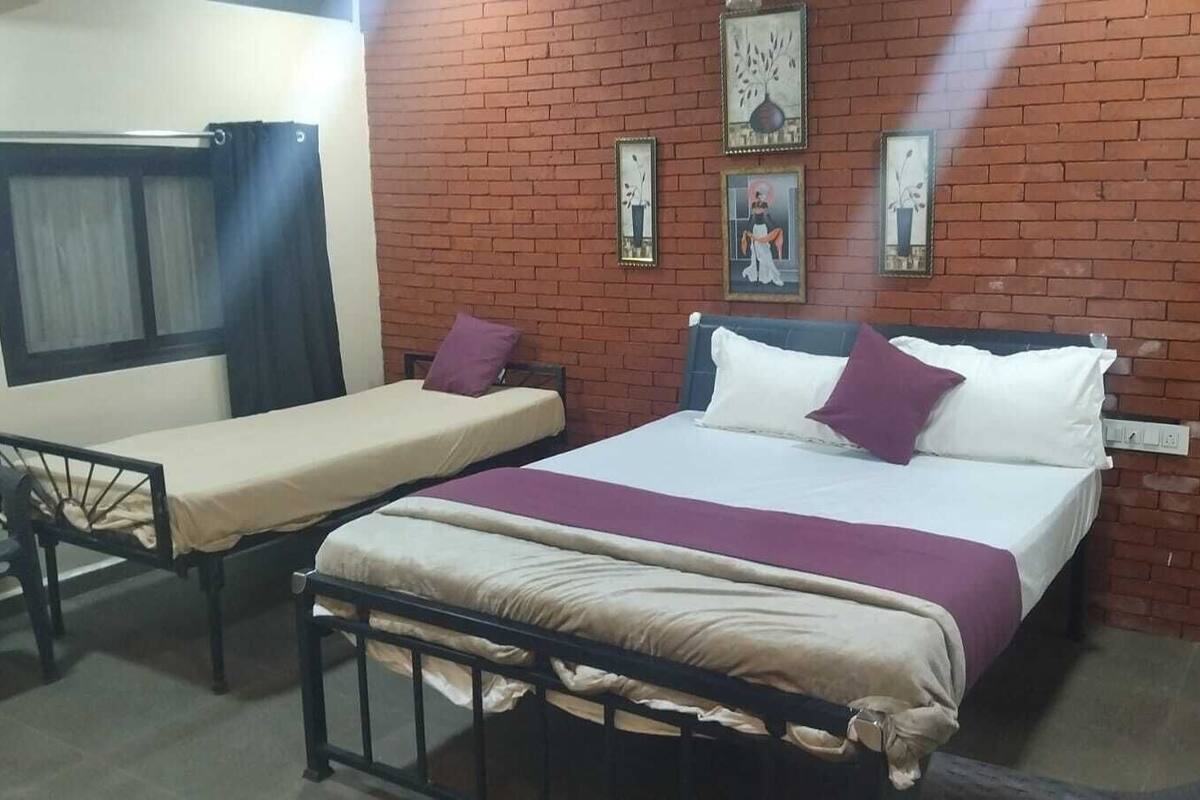 Ein Zimmer mit zwei Betten, einem Vorhangfenster und einer Ziegelwand.