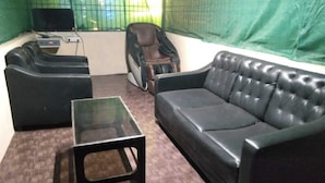 Een kamer met een zwarte leren bank, een bijpassende fauteuil en een kleine glazen tafel.
