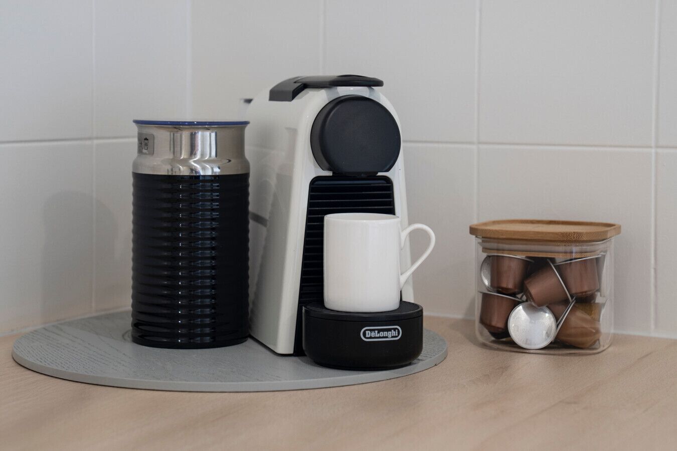 A coffee maker, a water bottle, and a container with spoons on a kitchen counter.