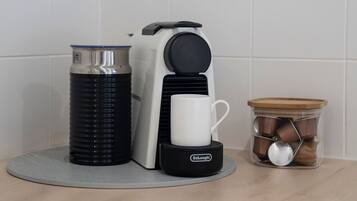 A coffee maker, a water bottle, and a container with spoons on a kitchen counter.