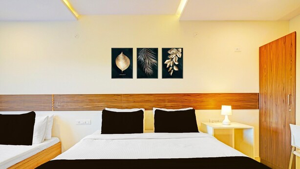 A hotel room with a large bed, two bedside tables, a wooden headboard, and wall art. - Deluxerenigunta Near Railway Station (Bengaluru)