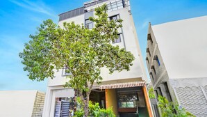 A multi-story building with a tree in front, a visible entrance, and a clear sky. - Deluxerenigunta Near Railway Station (Bengaluru)
