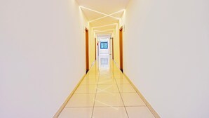 A long, narrow hallway with a shiny tiled floor and a ceiling with linear light fixtures. - Deluxerenigunta Near Railway Station (Bengaluru)