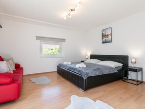 A bedroom with a bed, a red sofa, a window, and a painting on the wall. - Spacious vacation home where your dog is welcome (Radfeld)
