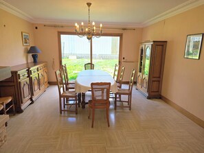A dining room with a table, chairs, a chandelier, a cabinet, and a view of the outdoors. - Bretagne large seaside house (Moëlan-sur-Mer)