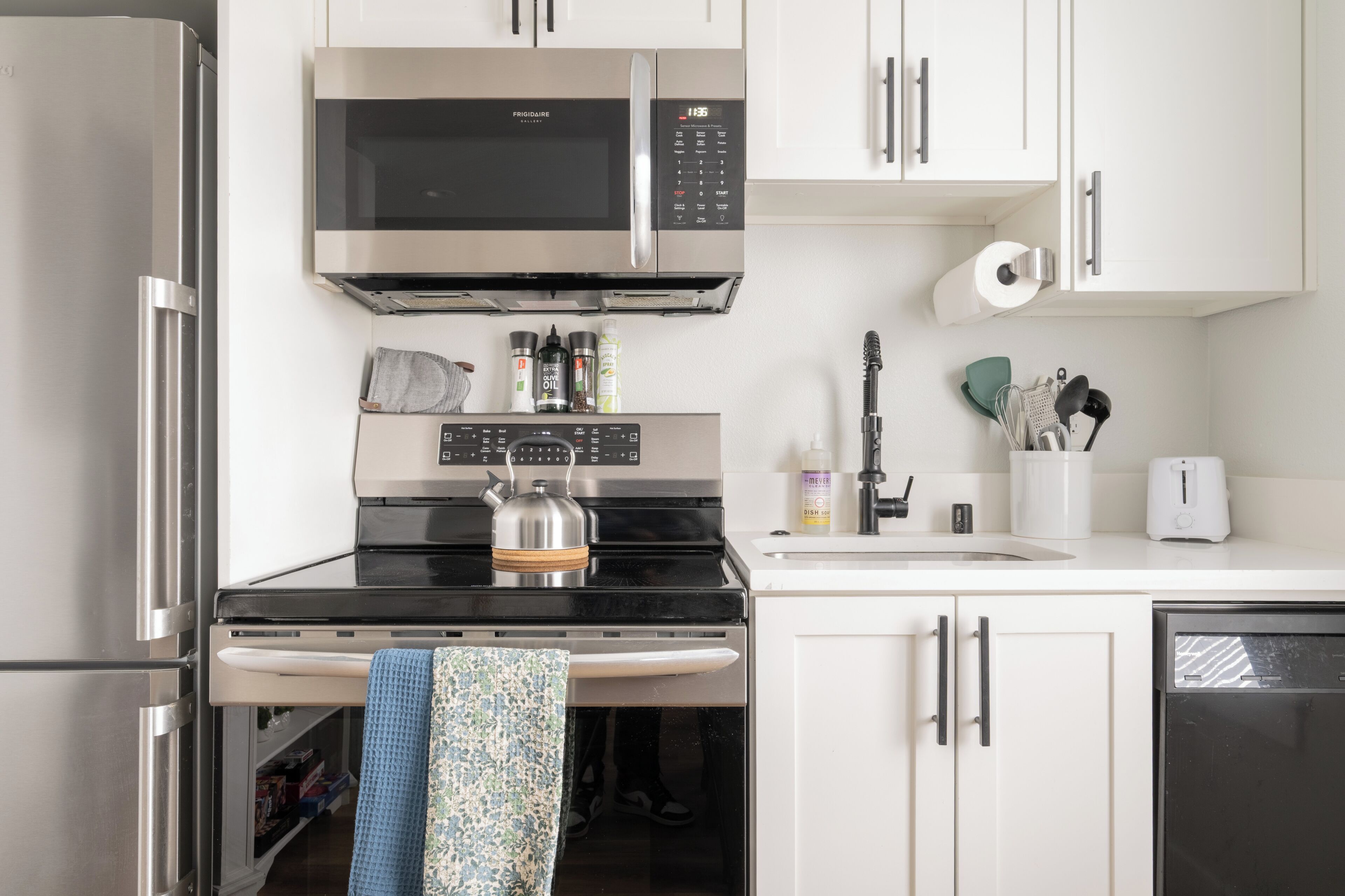 A kitchen with a stainless steel refrigerator, a microwave, a stove, and a dishwasher.