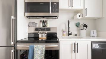 A kitchen with a stainless steel refrigerator, a microwave, a stove, and a dishwasher.
