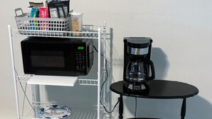 A kitchen area with a microwave, coffee maker, and storage shelves. - Saffire Villa  (Tacoma)