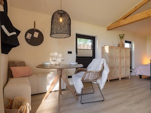 A cozy room with a round dining table, two chairs, a hanging light fixture, a wardrobe, and a sofa. - Romantic stay with private garden & sun loungers (Gapinge)