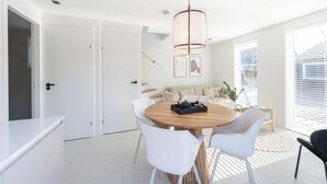 Een moderne eethoek met een ronde tafel, witte stoelen en een hanglamp.