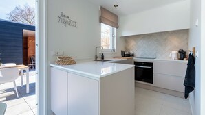Een moderne keuken met een centraal eiland, een inbouwoven en een backsplash van visgraatmozaïek.