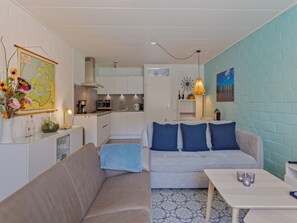 Ein modernes Wohnzimmer mit einer Couch, einem Couchtisch und einer Küche im Hintergrund.