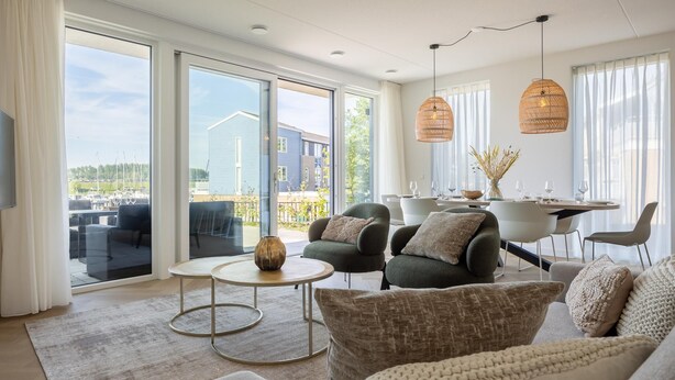 A modern living room with a sofa, armchairs, a coffee table, and a dining area with a table and chairs. - Harbour appartment with private garden (Kortgene)
