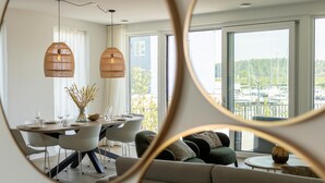 A modern dining area with a round table, chairs, and hanging rattan lamps. - Harbour appartment with private garden (Kortgene)