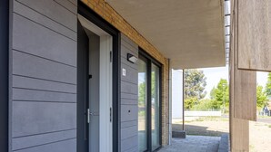 A modern building with a covered entrance, a door with a number plate, and a paved walkway. - Harbour appartment with private garden (Kortgene)