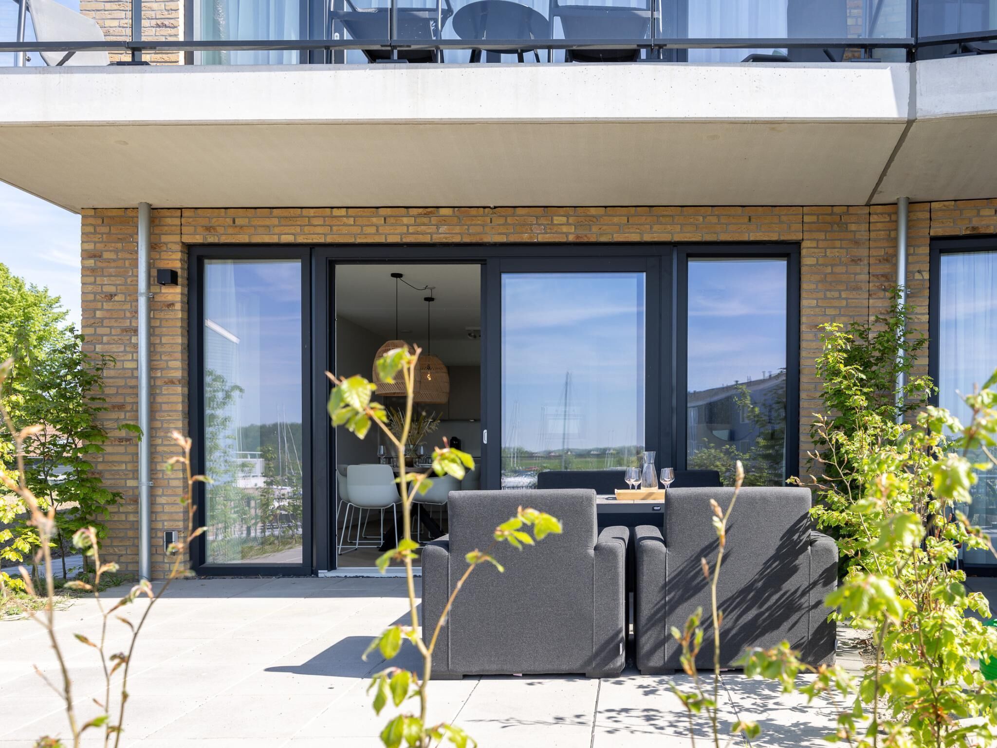 Een modern gebouw met een balkon, grote ramen en terraszitplaatsen.