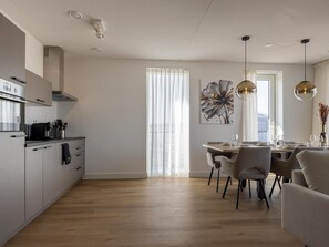 Une cuisine moderne avec un coin repas, un plancher en bois et des luminaires suspendus.