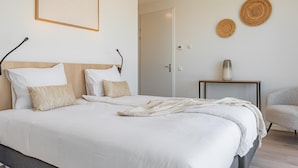A bedroom with a bed, bedside tables, a chair, and a door. - Luxury penthouse with terrace and harbour views (Kortgene)