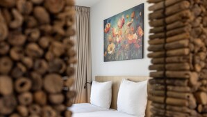 Una camera d'albergo con un letto, un quadro appeso al muro e una tenda.
