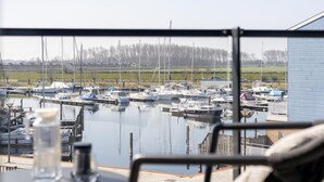 Un port de plaisance avec des bateaux amarrés, un ciel dégagé et un bâtiment en arrière-plan.
