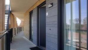 Un bâtiment moderne doté d’une galerie couverte, de grandes fenêtres et d’une porte portant l’inscription « 8A ».