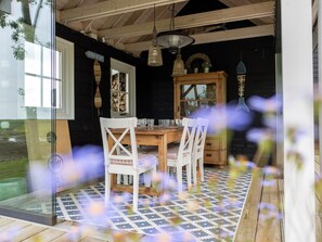 A wooden dining table with chairs, a hanging light fixture, and a patterned rug. - Villa with private pool on the Eastern Scheldt (Wissenkerke)
