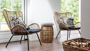 A room with two wicker chairs, a small round stool, and a wicker basket. - Villa with private pool on the Eastern Scheldt (Wissenkerke)