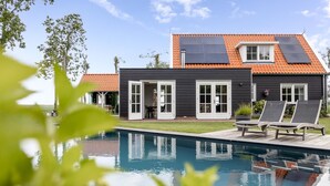A modern house with a swimming pool, solar panels, and a garden. - Villa with private pool on the Eastern Scheldt (Wissenkerke)