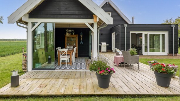 A house with a covered porch, a dining area with chairs, a grill, and potted plants. - Villa with private pool on the Eastern Scheldt (Wissenkerke)