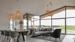 En modern inredning med ett matområde, en soffa och stora fönster med utsikt.
